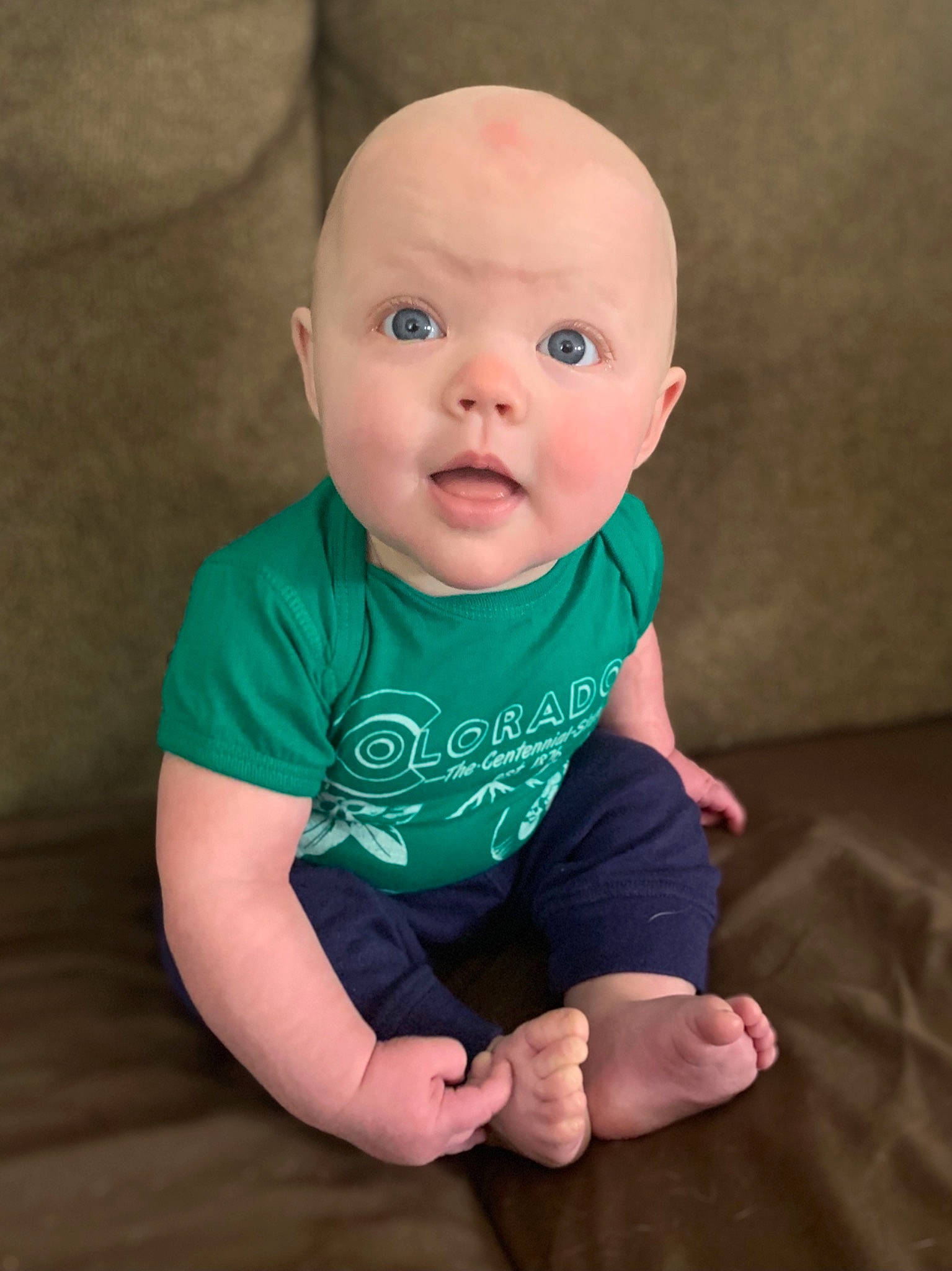 Bo is registered to the contest to win money with this photo: baby, baby_toddler_clothing, cheek, comfort, eye, flash_photography, floor, flooring, fun, happy, human_body, iris, lip, neck, nose, person, sitting, sleeve, smile, surprise