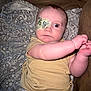 baby, infant, eye_patch, blanket, yellow_clothing, onesie, diaper, arm, face, wide_eyes, patterned_blanket, indoor, couch, cute, child, expression, skin, person, young, lying_down