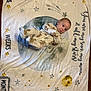 baby, infant, blanket, onesie, animal_print, stars, moon, text, floor, carpet, lying_down, cute, child, portrait, soft_texture, pattern, sleepwear, newborn, face, eyes