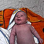 baby, infant, smiling, towel, orange_towel, white_towel, diaper, skin, cute, happy, lying_down, newborn, child, face, head, expression, indoors, blanket, small_person, wrapped