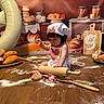 toddler, baby, child, baking, rolling_pin, flour, bread, pastries, balloon, number_9, table, wooden_floor, apron, chef_hat, celebration, sign, kitchen, food, indoors, portrait