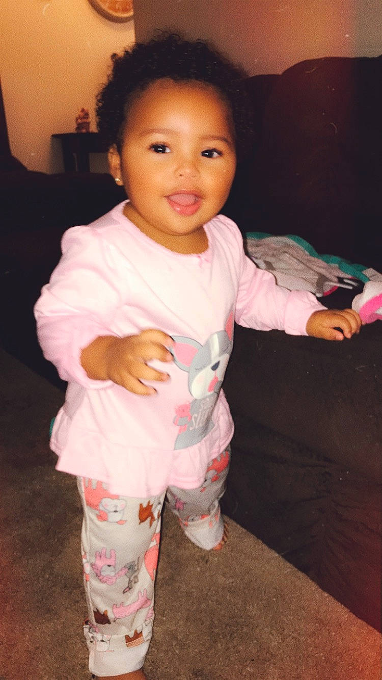 Jaida is registered to the contest to win money with this photo: arm, baby, cheek, child, lip, person, pink, skin, smile, standing, thumb, toddler