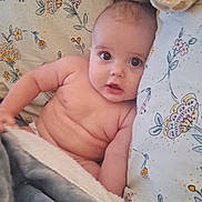 Mattéo participe au concours pour gagner de l'argent avec cette photo : baby, infant, blanket, pillow, stuffed_animal, floral_pattern, bed, cute, child, skin, soft_toy, lying_down, indoors, cozy, young, portrait, expression, comfort, toddler, resting