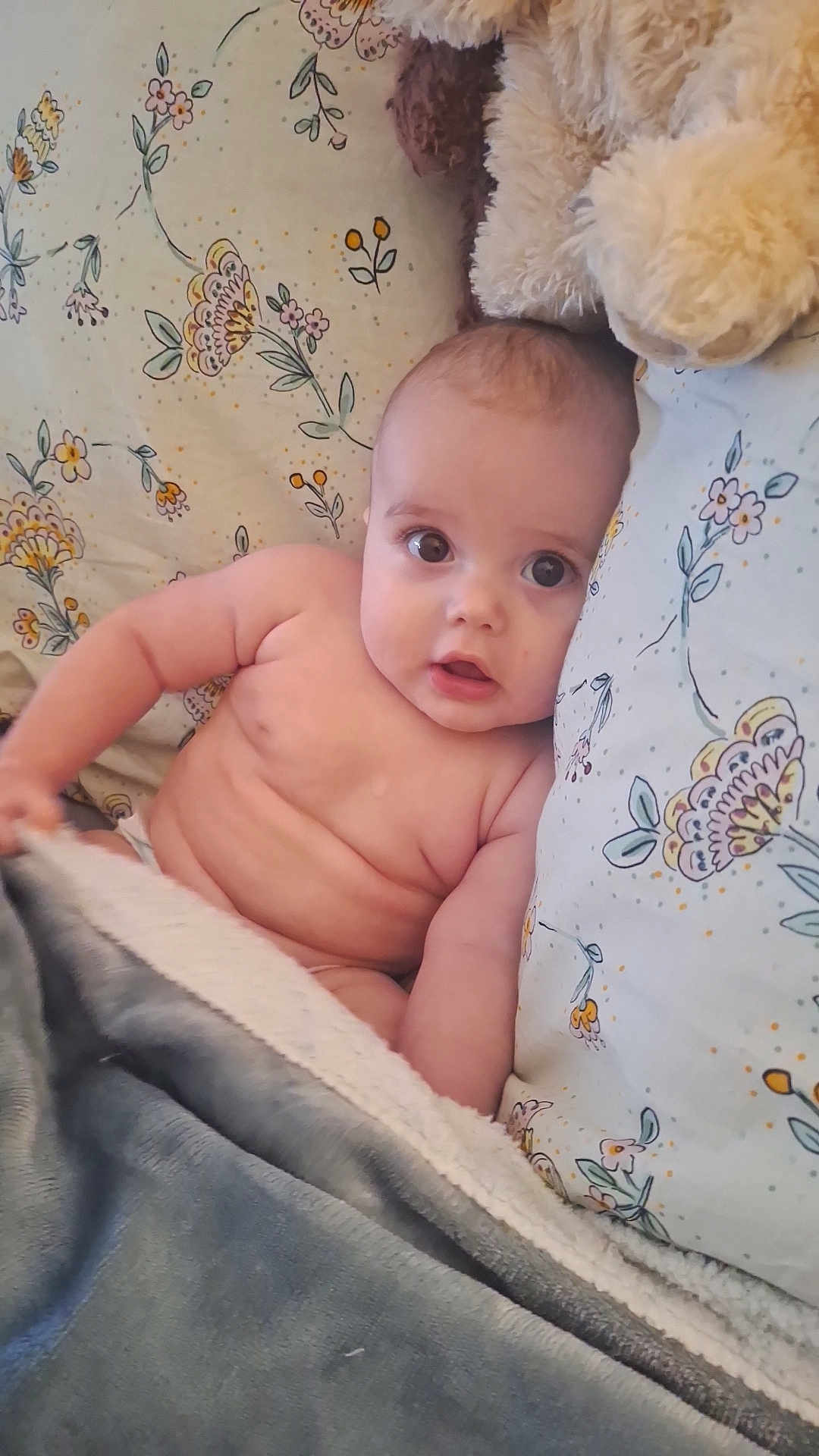 Mattéo participe au concours pour gagner de l'argent avec cette photo : baby, infant, blanket, pillow, stuffed_animal, floral_pattern, bed, cute, child, skin, soft_toy, lying_down, indoors, cozy, young, portrait, expression, comfort, toddler, resting