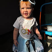 Meadow joined the competition — help win amazing prizes! child, toddler, baby, headband, bow, dress, skirt, onesie, smile, dimple, face, sunlight, shadow, indoor, wooden_floor, toy_trampoline, basket, standing, hand, accessory