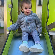 Layana a rejoint le concours — aidez-le/la à gagner de superbes lots ! casual_clothing, child, face, green_play_structure, happy, jacket, metal_slide, outdoor, park, play_equipment, playground, portrait, sitting, slide, smiling, sneakers, socks, striped_leggings, toddler, young_child