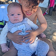 Layana participe au concours pour gagner de l'argent avec cette photo : baby, child, sibling, beach, sand, smile, curly_hair, outdoor, playful, cute, sunlight, casual_clothing, barefoot, happy, graffiti, toy, portrait, hug, summer, family
