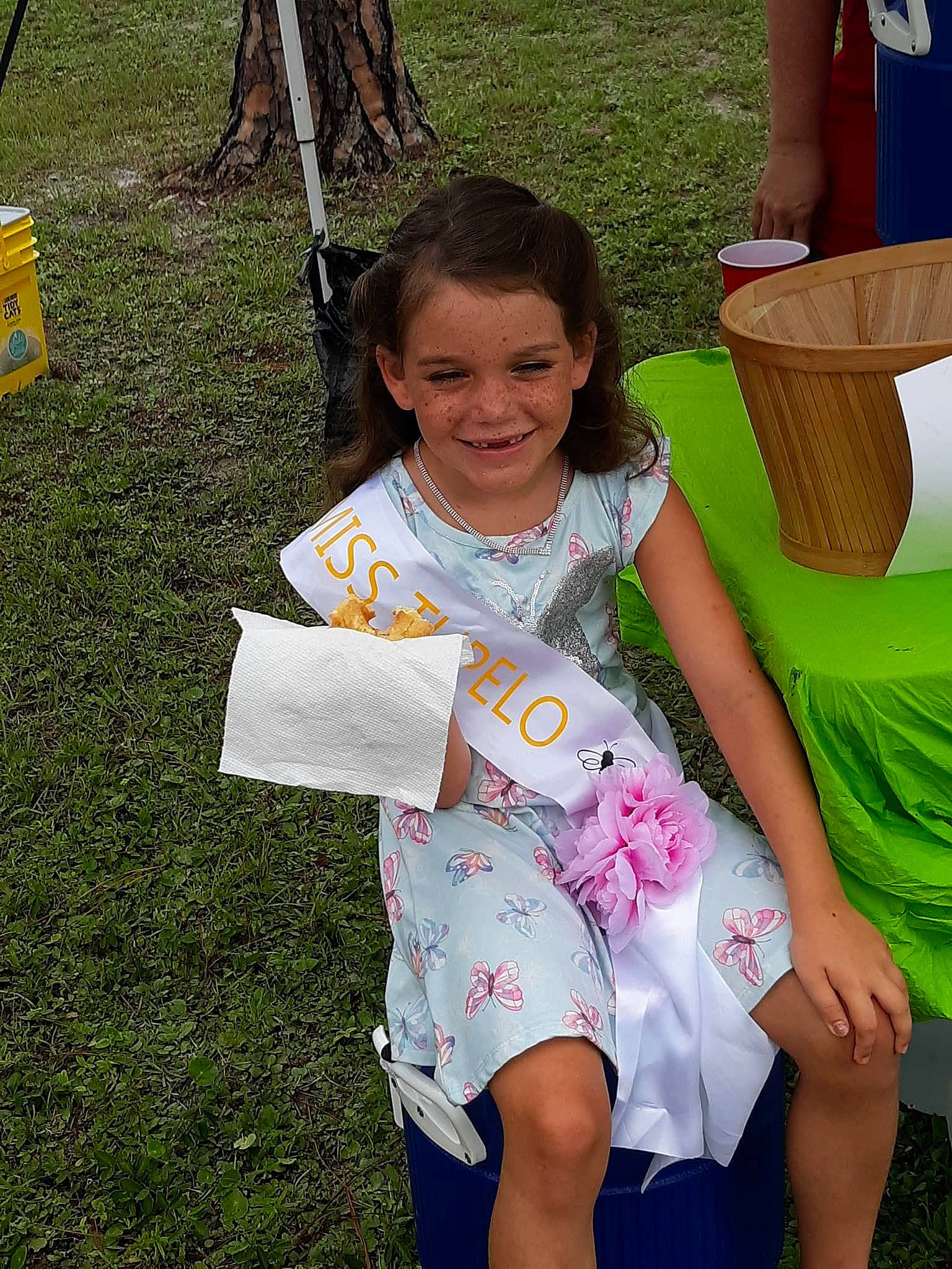 Kaylynn is registered to the contest to win money with this photo: barefoot, child, event, flip_flops, foot, fun, grass, happy, human_leg, joy, leisure, people_in_nature, person, play, recreation, shorts, sitting, smile, t_shirt, thigh