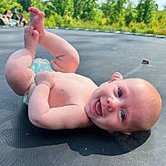 Waylon joined the competition — help win amazing prizes! baby, infant, smiling, blue_eyes, bare_chest, diaper, trampoline, outdoor, greenery, grass, sunlight, playful, happy, skin, child, nature, summer, cute, lying_down, feet_up
