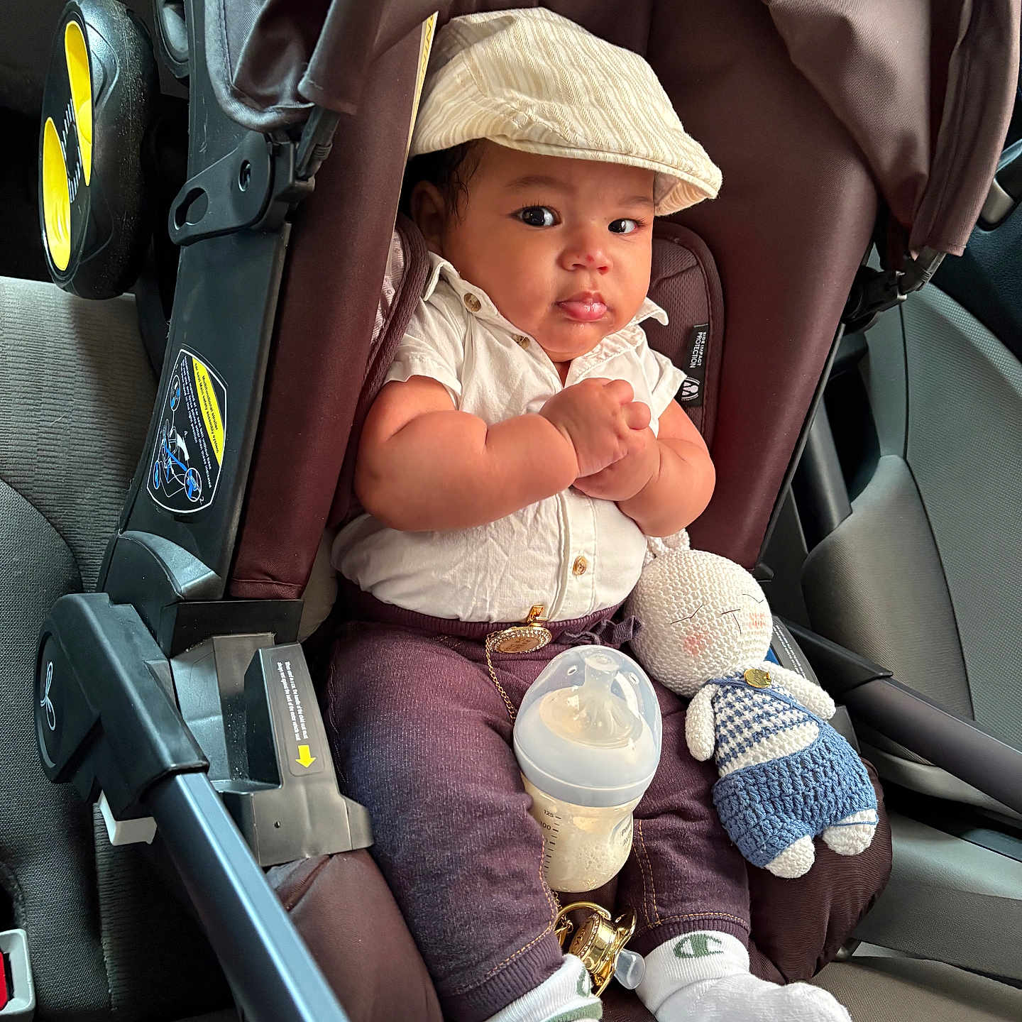 Eykel is registered to the contest to win money with this photo: baby, car_seat, infant, cap, white_shirt, knitted_doll, baby_bottle, car_interior, seatbelt, clothing, cute, child, socks, toy, portrait, young_child, casual, indoor, car, seat