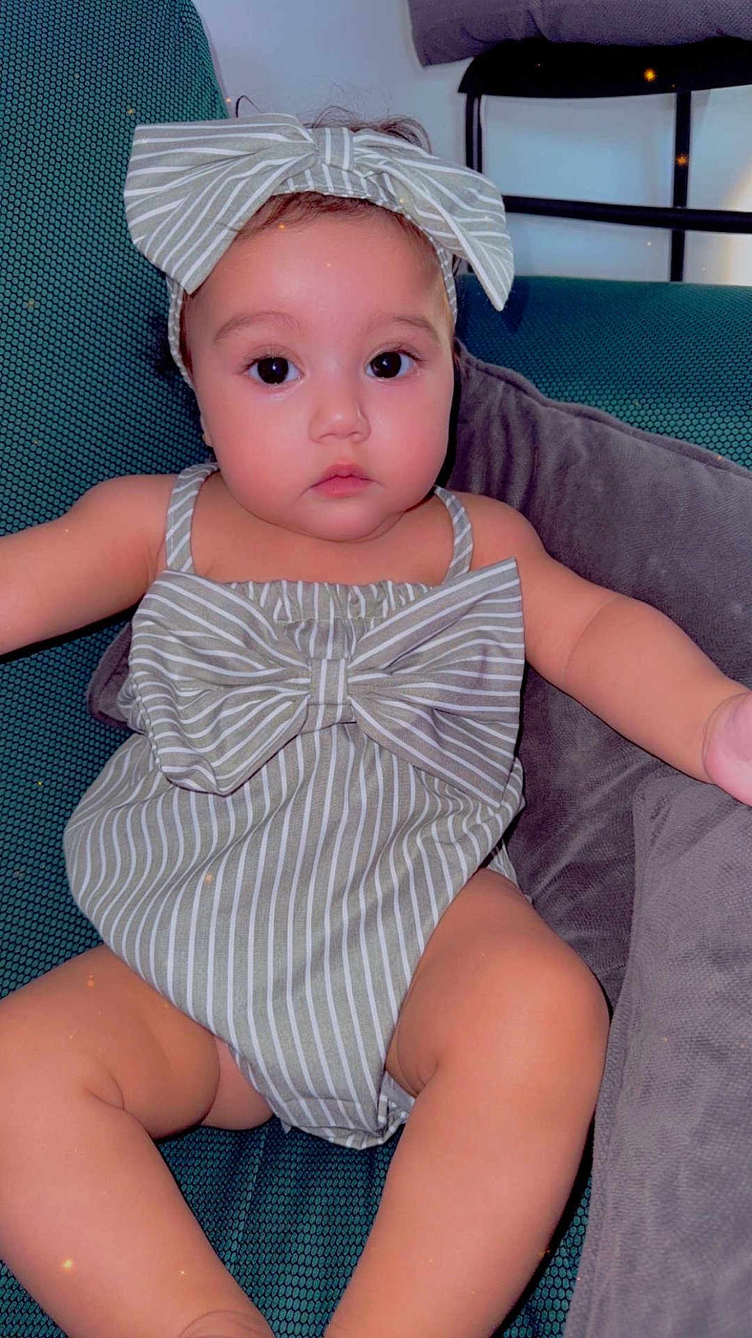 Lycia participe au concours pour gagner de l'argent avec cette photo : baby, child, bow, headband, romper, striped_clothing, chair, cushion, indoors, cute, person, infant, relaxed, seated, plump, skin, face, eyes, arm, legs