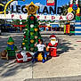 Rhylan Sarjoo is registered to the contest to win money with this photo: legoland, lego, child, boy, christmas_tree, santa_figure, elf_figure, park_entrance, signage, decorations, gifts, outdoors, pavement, playful, tourist_attraction, sunny, smiling, casual_clothing, sneakers, holiday_theme