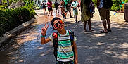 Rhylan Sarjoo joined the competition — help win amazing prizes! child, boy, sunglasses, peace_sign, backpack, sandals, waterpark, volcano, waterfall, palm_trees, summer, vacation, tourists, pathway, shadow, greenery, family, amusement_park, concrete, playful_pose