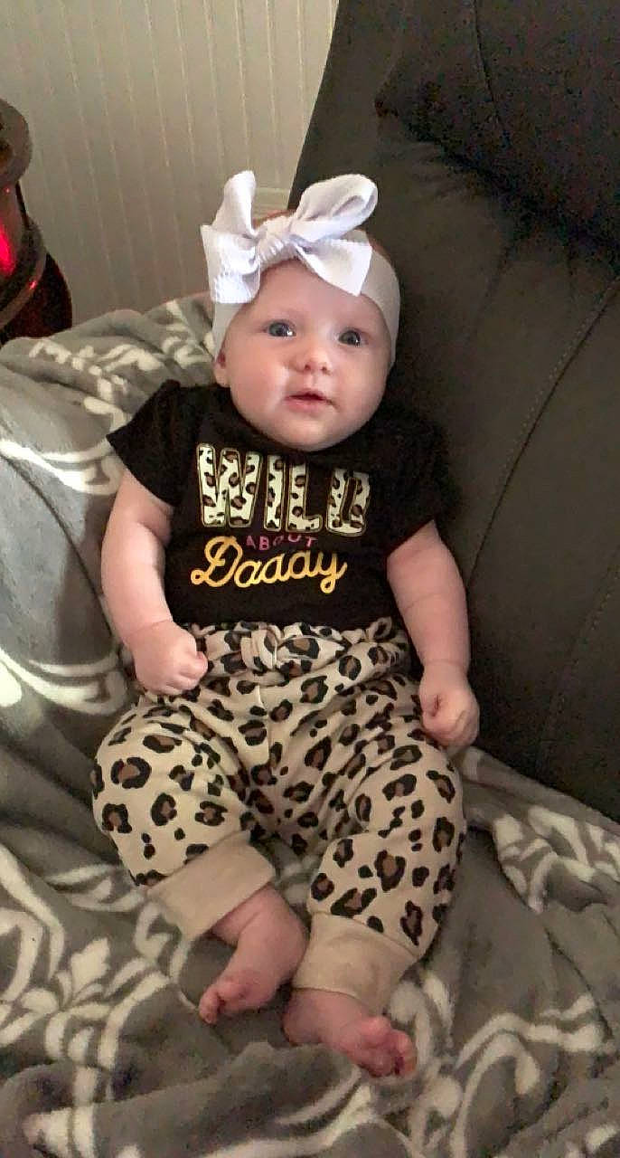 Brinleigh is registered to the contest to win money with this photo: arm, baby, baby_toddler_clothing, cap, chair, child, comfort, costume_hat, facial_expression, fawn, head, headwear, human_body, knee, leg, person, pink, skin, sleeve, t_shirt