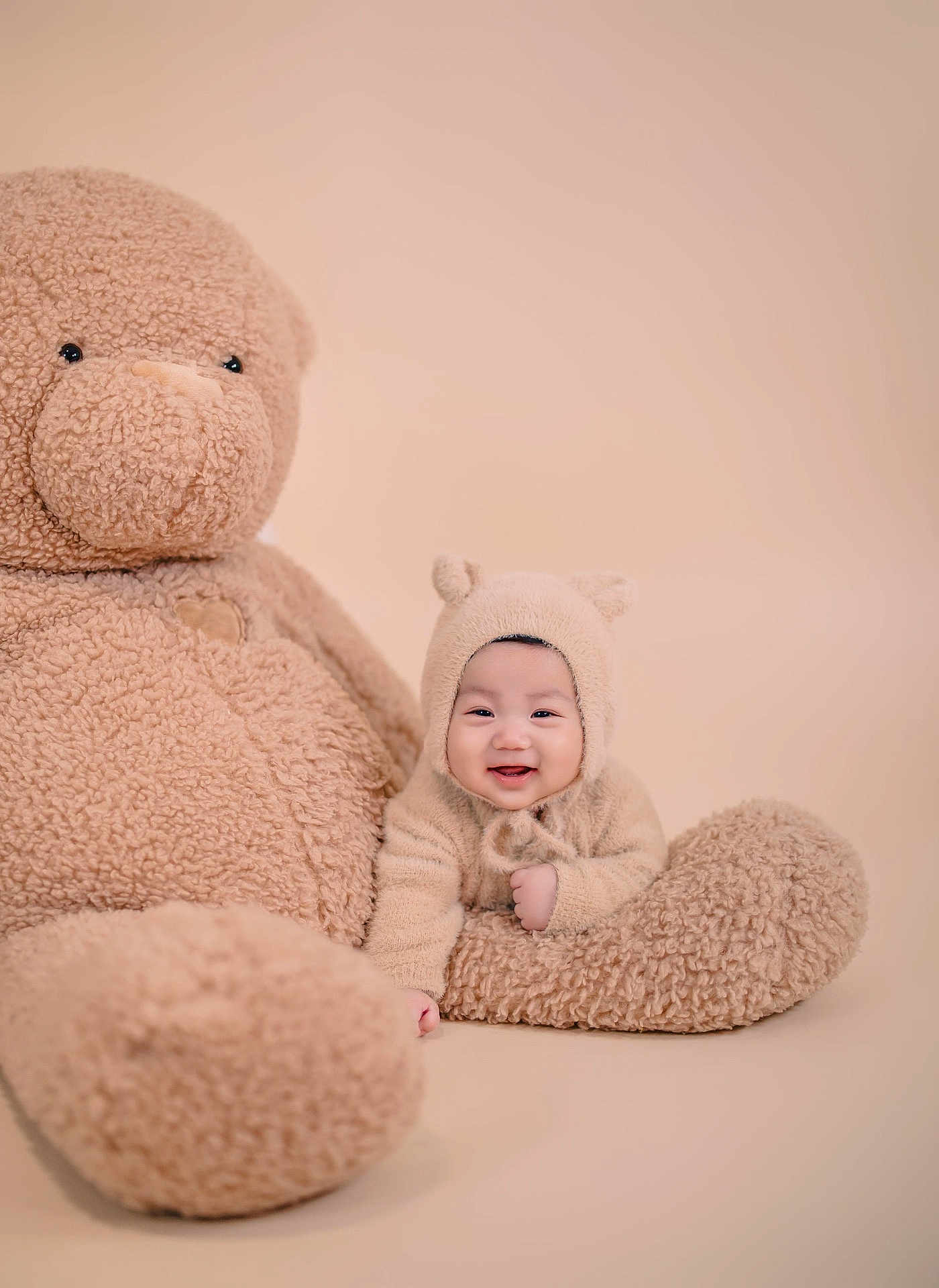 Ian joined the competition — help win amazing prizes! baby, teddy_bear, plush_toy, smiling, cute, fuzzy, beige, soft_texture, child, portrait, indoors, cozy, hat, happy, toy, sitting, infant, warm, cuddly, studio