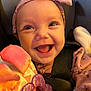 baby, smiling, headband, car_seat, toy, clothing, happy, face, child, infant, seatbelt, purple, pink, cute, closeup, cheerful, indoors, portrait, warm_lighting, infant_toy