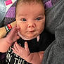 baby, infant, face, hand, blanket, clothing, onesie, purple, black, person, human, cute, expression, chubby_cheeks, indoor, portrait, young_child, holding, motion_blur, casual