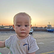 Juan joined the competition — help win amazing prizes! toddler, child, baby, outdoor, sunset, parking_lot, car, shirt, messy, person, face, expressionless, holding, urban, sky, building, blurred_background, short_sleeve, casual, daylight
