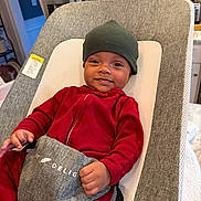 Marley joined the competition — help win amazing prizes! baby, infant, smiling, red_clothing, green_hat, baby_seat, gray_fabric, kitchen, stainless_steel, appliance, indoor, child, person, cozy, comfort, modern, seat, happy, home, portrait