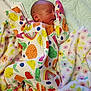 newborn, baby, sleeping, onesie, fruit_pattern, blanket, floral_blanket, cozy, infant, cute, soft_texture, child, sleep, peaceful, colorful_clothing, indoors, portrait, resting, young, person