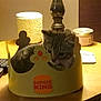 Groot joined the competition — help win amazing prizes! kitten, cat, burger_king_crown, lamp, table, wood, candle, tin_container, indoor, pet, feline, cozy, curious, domestic_animal, brown, striped, decor, soft_light, household, resting