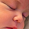 baby, sleeping, newborn, infant, face, portrait, close_up, peaceful, indoors, soft_lighting, skin, eyelashes, eyebrows, nose, lips, cheeks, blanket, clothing, resting, photography