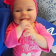 Lylianna joined the competition — help win amazing prizes! baby, baby_girl, blue_fabric, child, clothing, cushion, cute, face, hand_in_mouth, happy, headwear, indoors, infant, patterned_background, person, pink_headband, pink_shirt, portrait, sitting, smiling