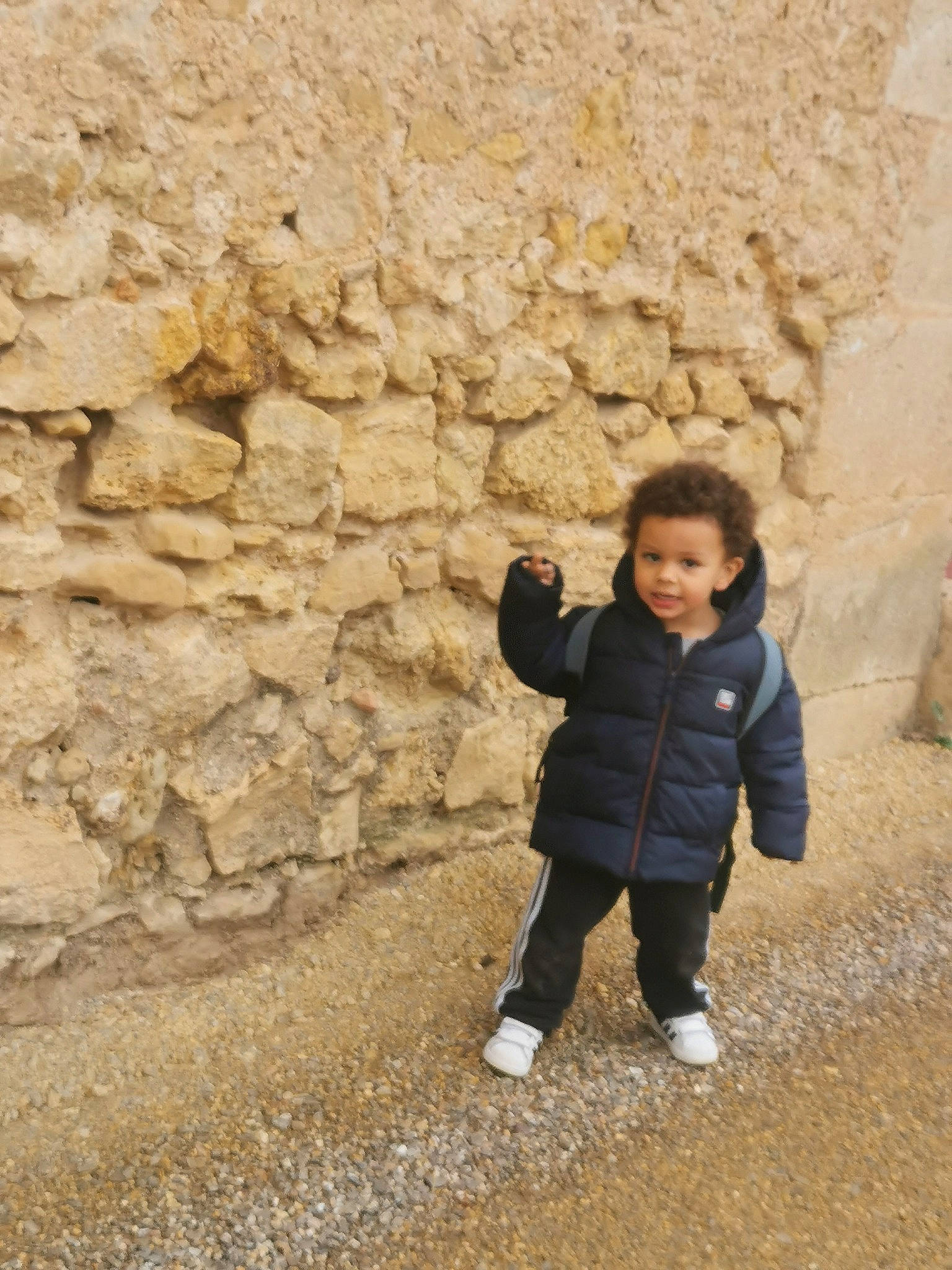 Hayden participe au concours pour gagner de l'argent avec cette photo : bedrock, child, cobblestone, flooring, fun, grass, jacket, landscape, leisure, people_in_nature, person, road_surface, rock, shadow, sitting, soil, stone_wall, toddler, tree, winter