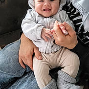 Amenadiel a rejoint le concours — aidez-le/la à gagner de superbes lots ! baby, smiling, hoodie, socks, adult_hand, couch, jeans, person, indoor, cute, knitted_socks, happy, child, cozy, infant, holding_hands, soft_clothing, toddler, footwear, blanket