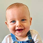 Sacha participe au concours pour gagner de l'argent avec cette photo : baby, child, smiling, face, blue_eyes, denim_overalls, white_shirt, portrait, cute, happy, infant, closeup, skin, hair, person, young_child, light_background, indoor, button, clothing