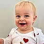baby, child, smiling, blue_eyes, onesie, red_hearts, holding, hand, face, happy, cute, blond_hair, infant, portrait, sitting, light_background, skin, person, young_child, expression