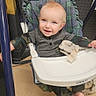 baby, blue_eyes, camouflage, child, comfort, cute, floor, gray_clothing, happy, high_chair, indoor, infant, metal_frame, person, play_area, plush_blanket, seat, smiling, swing, yellow_marking