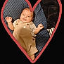 adorable, baby, black_background, blue_cushion, child, clothing, cozy, cute, hands_up, heart_frame, indoor, infant, overalls, pattern, person, portrait, relaxed, smile, soft_texture, young_child