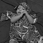 Stella is registered to the contest to win money with this photo: baby, child, infant, blanket, cloth, patterned_cloth, watermelon_pattern, lying_down, hand, face, expression, carpet, soft_surface, indoors, monochrome, black_and_white, cute, young_child, portrait, resting