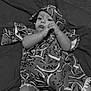 baby, child, infant, blanket, cloth, patterned_cloth, watermelon_pattern, lying_down, hand, face, expression, carpet, soft_surface, indoors, monochrome, black_and_white, cute, young_child, portrait, resting