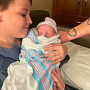 Gunnison is registered to the contest to win money with this photo: child, newborn, baby, hospital, blanket, towel, tattoo, hand, bed, couch, portrait, family, love, indoor, closeup, person, smile, care, holding, sibling