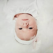 Alix participe au concours pour gagner de l'argent avec cette photo : baby, face, headband, flower, white_clothing, fluffy, soft_texture, portrait, child, infant, cute, lying_down, close_up, skin, young, innocent, head, eyes, adorable, peaceful