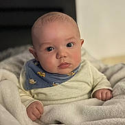Kenny participe au concours pour gagner de l'argent avec cette photo : baby, infant, blanket, blue_bib, clothing, face, person, portrait, cute, chubby_cheeks, indoors, soft_texture, warm, child, young, sitting, curious, wide_eyes, head, hands
