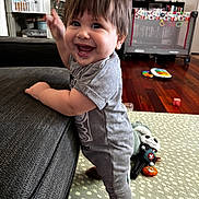 William joined the competition — help win amazing prizes! toddler, child, smiling, standing, couch, living_room, toy, floor_mat, happy, indoor, hair, clothing, person, face, playful, home, furniture, carpet, baby, expression