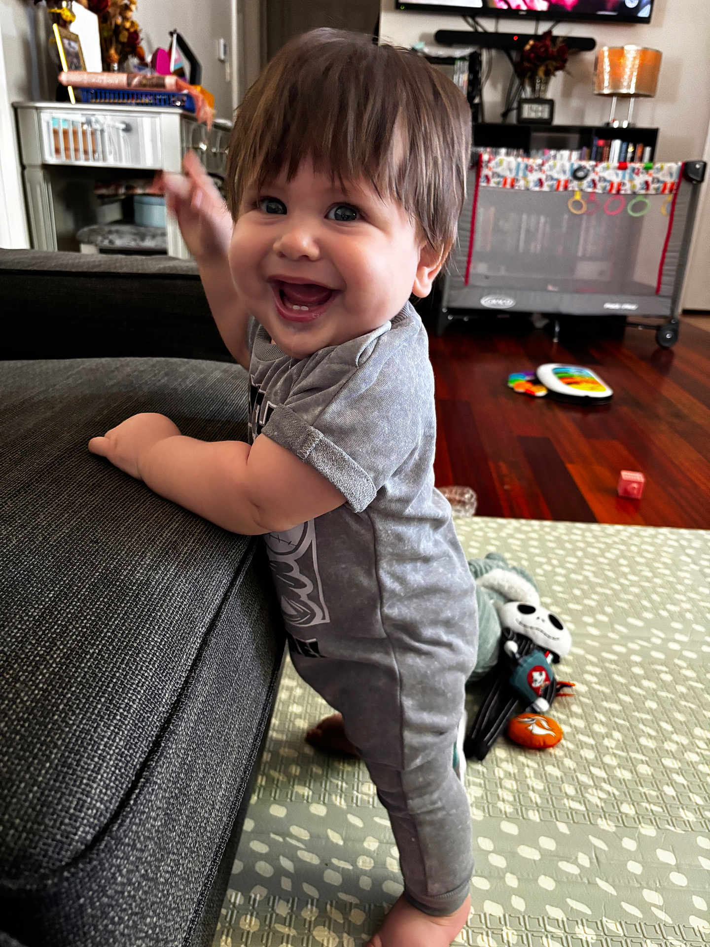 William joined the competition — help win amazing prizes! toddler, child, smiling, standing, couch, living_room, toy, floor_mat, happy, indoor, hair, clothing, person, face, playful, home, furniture, carpet, baby, expression