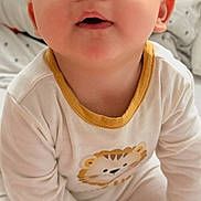 Eden a rejoint le concours — aidez-le/la à gagner de superbes lots ! baby, infant, child, face, eyes, onesie, lion_print, bed, pillow, cute, curious, sitting, indoors, soft_lighting, portrait, young_child, hands, expression, clothing, cozy