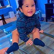 Thiago is registered to the contest to win money with this photo: toddler, child, smiling, blue_shirt, plaid, socks, glass_table, indoor, floor, hand, person, happy, face, hair, wood_floor, furniture, room, baby, cute, young