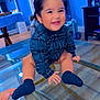 toddler, child, smiling, blue_shirt, plaid, socks, glass_table, indoor, floor, hand, person, happy, face, hair, wood_floor, furniture, room, baby, cute, young