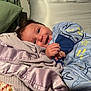 Greyson joined the competition — help win amazing prizes! baby, smiling, blanket, onesie, blue_clothing, bed, pillow, soft_texture, indoor, happy, infant, child, face, hands, sleepwear, cute, comfort, resting, cozy, young