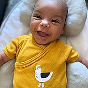 Noé participe au concours pour gagner de l'argent avec cette photo : baby, baby_boy, baby_girl, bird_print, child, closeup, cushion, cute, face, happy, head, indoors, infant, onesie, person, portrait, sitting, smiling, soft_furniture, yellow_clothing