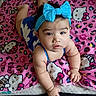 baby, child, headband, blue, bow, hello_kitty, blanket, pink, pattern, curious, face, infant, cute, indoors, person, skin, hand, lying_down, plush, clothing