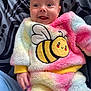 adorable, baby, bee_patch, blanket, blue_eyes, child, colorful, cozy, cute, fluffy_clothing, happy, infant, lying_down, patterned_background, portrait, smiling, soft_texture, tongue_out, warm_clothing, young_child