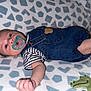 baby, infant, pacifier, denim_overalls, striped_shirt, blanket, pattern, couch, cute, child, small_hand, face, lying_down, indoors, soft_texture, adorable, newborn, clothing, resting, young