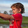 Bryson joined the competition — help win amazing prizes! child, toddler, curly_hair, red_shirt, dinosaur_graphic, outdoor, grass, sky, portrait, side_view, smiling, young_child, nature, casual_clothing, daylight, cute, playful, person, happy, fun