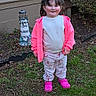 Kinsley is registered to the contest to win money with this photo: child, girl, pink_jacket, flamingo_pants, pink_shoes, backyard, grass, lighthouse_decoration, house_siding, smiling, standing, outdoor, casual_clothing, young_child, nature, greenery, daylight, portrait, person, cute